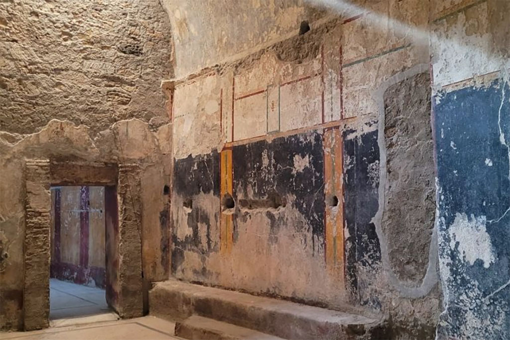 VII.5.8 Pompeii. March 2024. The changing room (46) with mosaic floor, frescoed walls and benches (47) looking through door into tepidarium (49).
Photograph © Parco Archeologico di Pompei.
