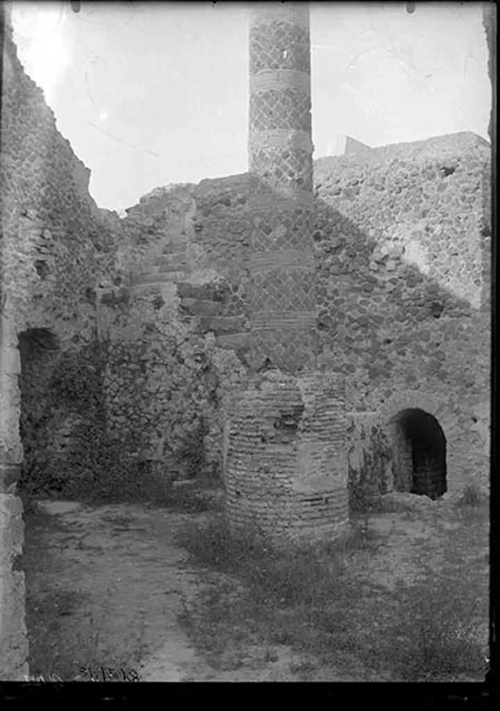 VII.5.10 Pompeii. 1931. Courtyard (33) with column (34), staircase (35) to caldarium, and entrance (36) to praefurnium (boiler) area.
DAIR 31.2528. Photo © Deutsches Archäologisches Institut, Abteilung Rom, Arkiv.
The courtyard is accessible off Vicolo delle Terme.
On the left is the entrance corridor (32) to the praefurnium.
The ramped masonry staircase (35) allows access to the roof of the caldarium.
The circular brick base had a column (34) erected on it after the earthquake, probably to support a sundial.
The smaller arch on the right is entrance (36) to praefurnium (boiler) area.
See Carratelli, G. P. ed., 1990-2003. Pompei: Pitture e Mosaici. Vol. VII. Roma: Istituto della enciclopedia italiana, p. 172.
Alternative sources, such as Niccolini, have suggested the column is a roof support.