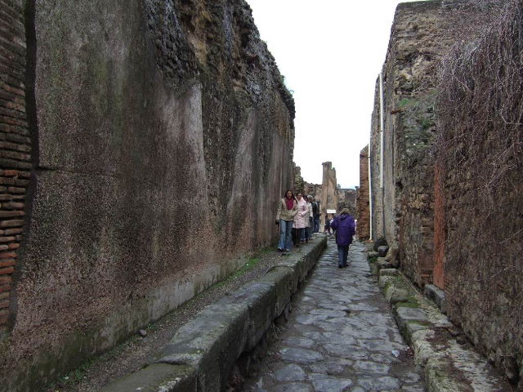 VII.6.17 Pompeii on the left. December 2006. Vicolo delle Terme looking north with VII.5 and Forum baths on the right. Between VII.6.16 and VII.6.17 are three large water storage reservoirs that feed the Forum Baths. These are behind the wall on the left. The tanks were 5m by 15m at the base and 9m high at the top of the curved roof. It is estimated the reservoirs held 430,000 litres of water. See Eschebach, L., 1993. Gebäudeverzeichnis und Stadtplan der antiken Stadt Pompeji. Köln: Böhlau. (p. 41).