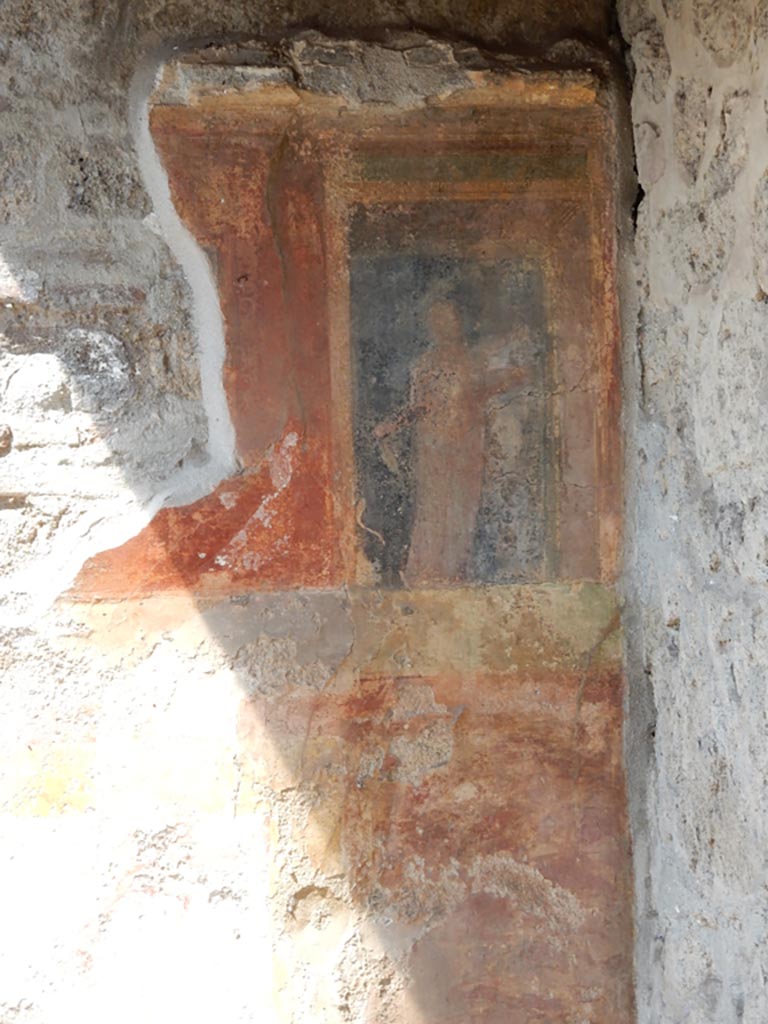 VII.7.5 Pompeii, May 2018. Oecus (m), west wall in north-west corner.
It is just possible to glimpse a female figure holding a plate of offerings in her left hand, on the black panel.
This would have been above a high zoccolo with panels of false painted marble.
See Sogliano, A., 1879. Le pitture murali campane scoverte negli anni 1867-79. Napoli: Giannini. (no.793)
Photo courtesy of Buzz Ferebee.
This would have been to the north of the doorway opening onto the east portico.