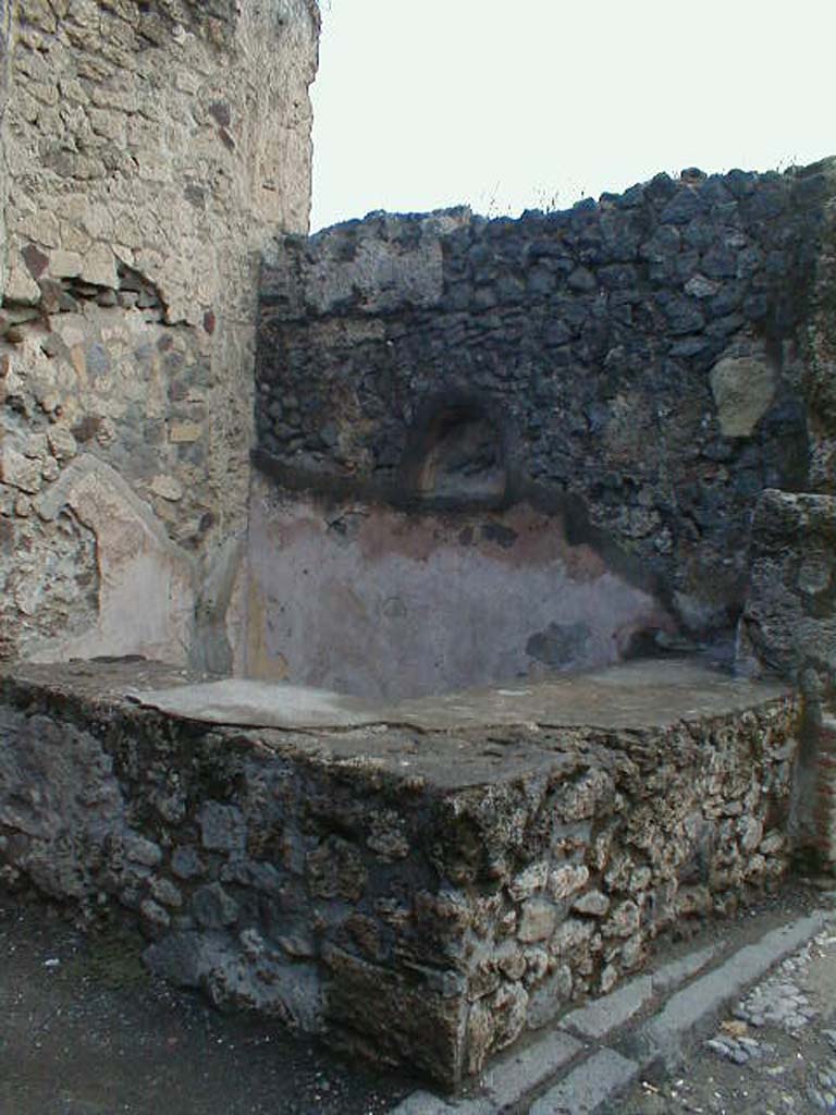 VII.7.11 Pompeii. September 2004. Two-sided sales counter, with niche for lararium in east wall.
According to Boyce, the inside walls of the arched niche were coated with yellow stucco.
See Boyce G. K., 1937. Corpus of the Lararia of Pompeii. Rome: MAAR 14. (p.68, no.298)