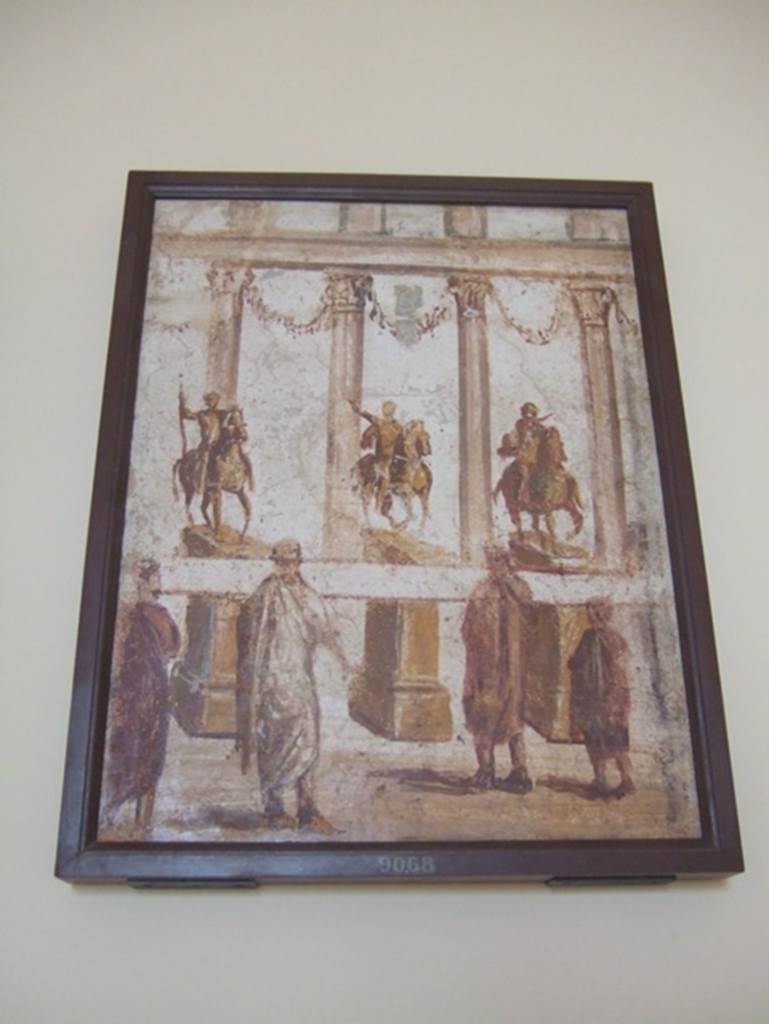 Part of the “Forum Frieze” found in the atrium of II.4.3.
Forum scene of people reading a banner across the front of the equestrian statues. Now in Naples Archaeological Museum. Inventory number 9068.