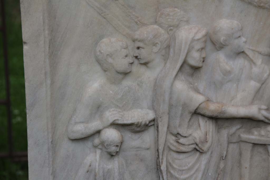 VII.9.2 Pompeii. April 2014. Detail from west side of Altar. Photo courtesy of Klaus Heese.
According to Mau, this shows a priest with a toga drawn over his head pours a libation from a shallow bowl or patera onto an altar.
On the left are two lectors with their bundles of rods, a flute player, two boys – camilli - carrying the utensils for the sacrifice, and also an attendant.
See Mau, A., 1907, translated by Kelsey F. W. Pompeii: Its Life and Art. New York: Macmillan. (Pages 106-7).