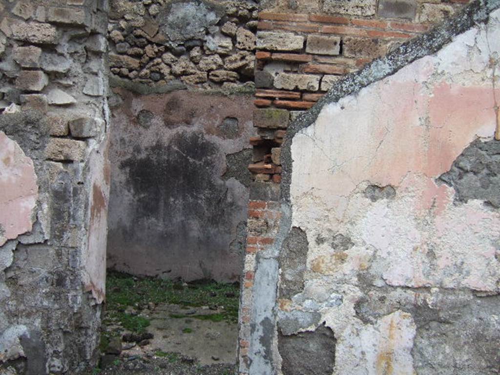 VII.10.3 Pompeii. December 2005. Doorway to room 5, a cubiculum on north side of atrium.
This room had a floor of red cocciopesto. The door threshold formed of two rectangular travertine slabs, was also marked in the centre with a circular recess for the fixing of the double-door hinges. When redecorated this room was repainted with red plaster walls, of which some traces remain. Its original flooring was kept.
Studi della Soprintendenza archeologica di Pompei, 22: l”Insula VII, 10 di Pompei, by Angelo Amoroso, (p.54 and p.74)