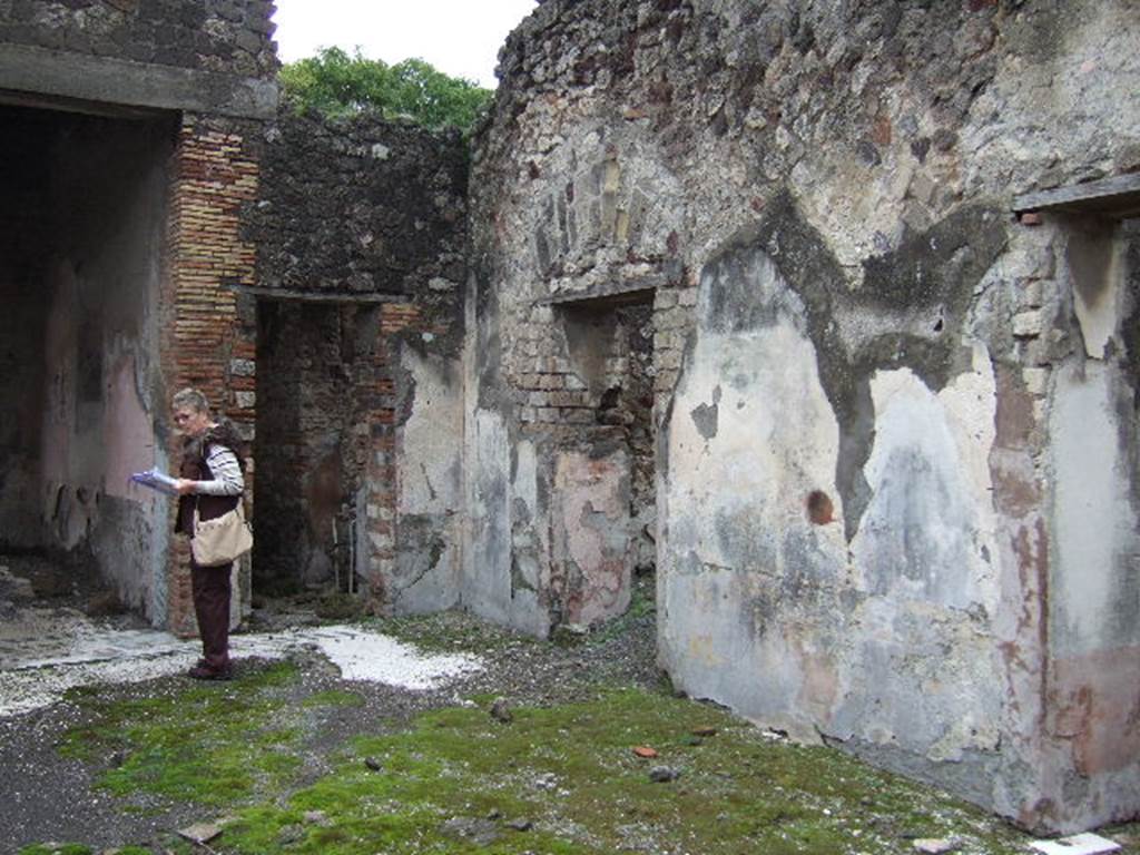 VII.10.3 Pompeii. December 2005. South-east corner of atrium with doorway to corridor 8 next to tablinum, and doorways to rooms 9 and 10 on south side of atrium. According to Breton, on the right of the tablinum was a corridor leading to a kitchen where a big iron bucket attached to a wall and the pipe used to fill it up, could still be seen. On the right was a painting of a woman holding a wand.
See Breton, Ernest. 1870. Pompeia, Guide de visite a Pompei, 3rd ed. Paris, Guerin.
According to Boyce, the woman held a rudder.
See Boyce G. K., 1937. Corpus of the Lararia of Pompeii. Rome: MAAR 14. (p.69, no.308)