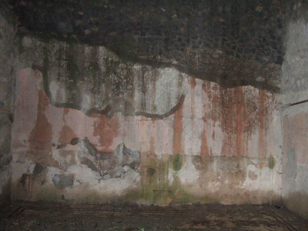 VII.10.3 Pompeii. December 2005. Room 14, east wall of exedra/oecus, at rear of peristyle garden. According to Fiorelli, two paintings were found in the exedra. One represented the head of Dionysus crowned with ivy leaves, with his head beside a Baccante appearing near his shoulder. The other was circular showing Perseus holding up the head of Medusa, to show the reflection in the water to Andromeda, who rests on his shoulder. On one side of the exedra are two other rooms, of which the second was used perhaps for a dormitory
See Pappalardo, U., 2001. La Descrizione di Pompei per Giuseppe Fiorelli (1875). Napoli: Massa Editore. (p.108)
According to Bragantini, the floor was black and white mosaic. In the centre was an emblema of opus sectile showing squares and triangles in coloured marbles. The walls were painted in the IVth style with a black zoccolo containing panels showing painted plants. The middle zone of the walls was red. On the south wall, in the centre of the black zoccolo was a yellow panel with painted plants. In the centre of the middle zone was a yellow panel with a painting, no longer recognisable.
See Bragantini, de Vos, Badoni, 1986. Pitture e Pavimenti di Pompei, Parte 3. Rome: ICCD. (p.177-8)
According to Richardson, found in the “triclinium” on the east side of the peristyle, were a painted bust of Bacchus and a maenad (Sommer negative 11918)
See Richardson, L., 2000. A Catalog of Identifiable Figure Painters of Ancient Pompeii, Herculaneum. Baltimore: John Hopkins. (p.127)
According to Helbig, found in the “triclinium” behind the peristyle was a painting of Perseus and Andromeda, (1198), and Bust of Dionysus, (385).
See Helbig, W., 1868. Wandgemälde der vom Vesuv verschütteten Städte Campaniens. Leipzig: Breitkopf und Härtel. (1198 and 385).
According to Amoroso, the exedra (our room 14) stood behind the viridarium and was decorated with a bacchic scene and with a pinax circolare in which were figured Perseus showing Andromeda the severed head of Medusa reflected in the water.
Studi della Soprintendenza archeologica di Pompei, 22: l”Insula VII, 10 di Pompei, by Angelo Amoroso, (p.274)