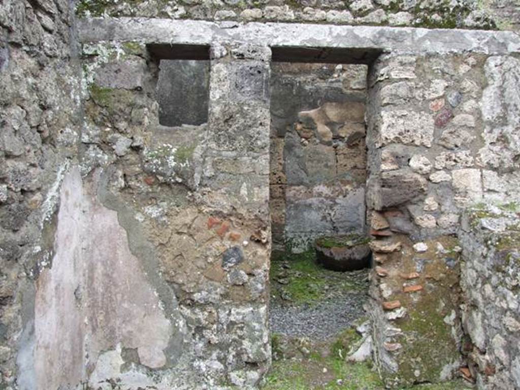 VII.10.12 Pompeii. March 2009. Looking west at wall with a door with plaster in the lower area.
