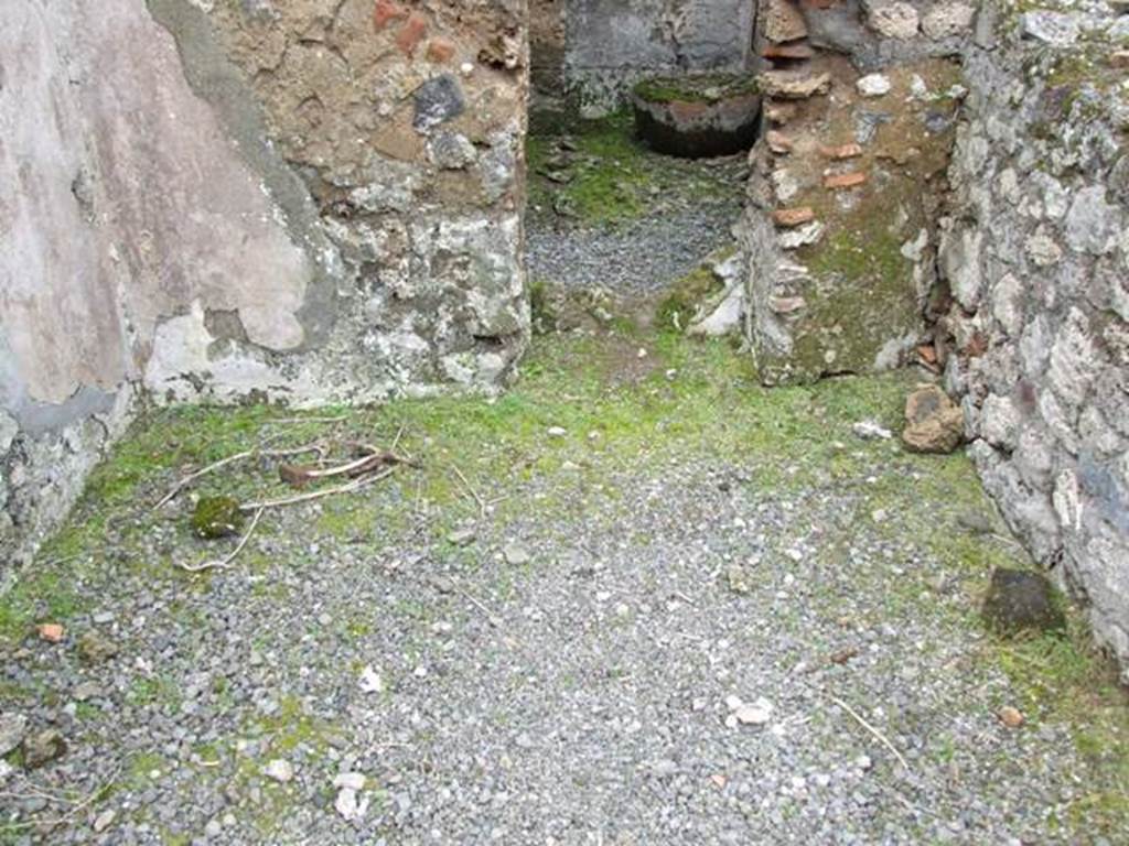 VII.10.12 Pompeii. March 2009. Looking west at floor and wall with a door with plaster in the lower area.