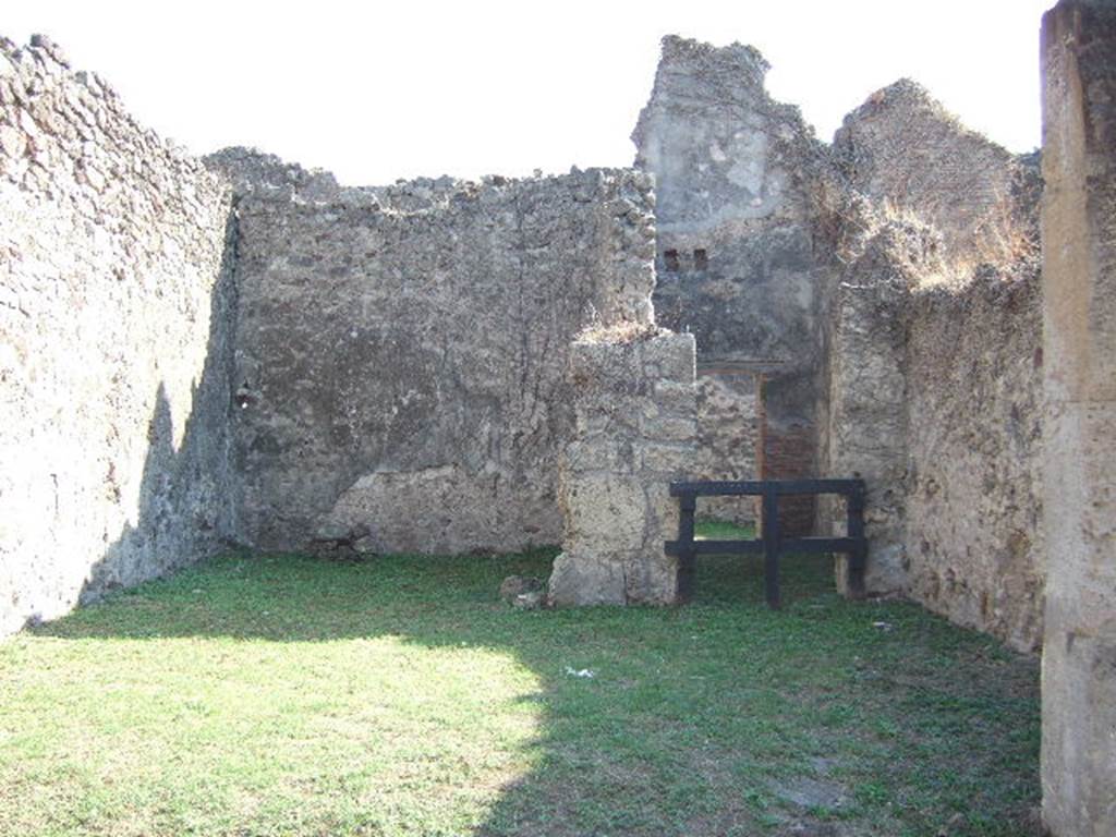 VII.12.10 Pompeii. September 2005. Looking south towards rear room of shop, on left. On the west wall of the rear room remains of IV style painting could be seen, including a red zoccolo and white middle area of the wall. On the right, were the stairs to upper floor and corridor to rear yard. According to Boyce, in the south-west corner of the rear area was a lararium. The lararium painting could be seen on the west wall of the kitchen above the hearth.
See Boyce G. K., 1937. Corpus of the Lararia of Pompeii. Rome: MAAR 14. (p.70, no.314)