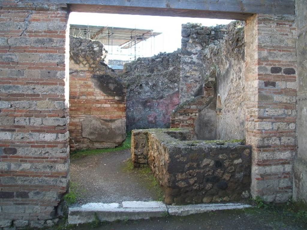 VII.12.15 Pompeii. December 2004. Entrance doorway and counter with hearth, and niche in west wall. At the rear is a doorway to a room used for the hospitality of the guests. See Della Corte, M., 1965. Case ed Abitanti di Pompei. Napoli: Fausto Fiorentino. (p.202)