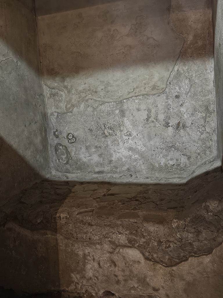VII.12.18 Pompeii. November 2024.
Detail of plaster on wall, and stone bed. Photo courtesy of Annette Haug.