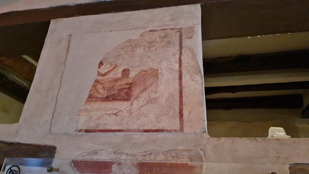 VII.12.18 Pompeii. April 2022. Part of remains of painted erotic wall fresco on frieze. Photo courtesy of Giuseppe Ciaramella.