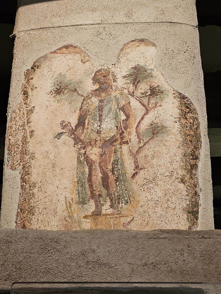 VII.12.18 Pompeii. November 2024.
Wall painting of Priapus in front of a fig tree, with double phallus, from the upper frieze in the middle of the north wall.
Photo courtesy of Annette Haug.