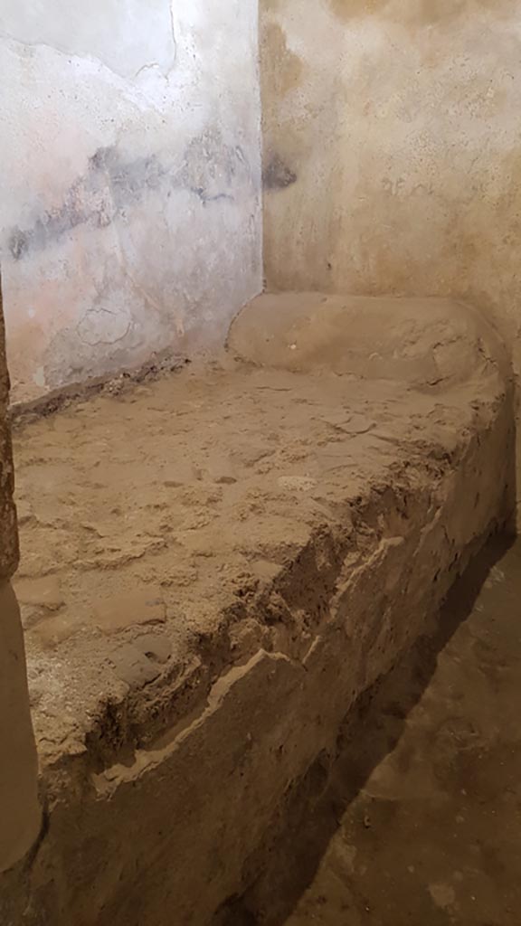 VII.12.8 Pompeii. August 2023.
Prostitutes room with stone bed. Photo courtesy of Maribel Velasco.