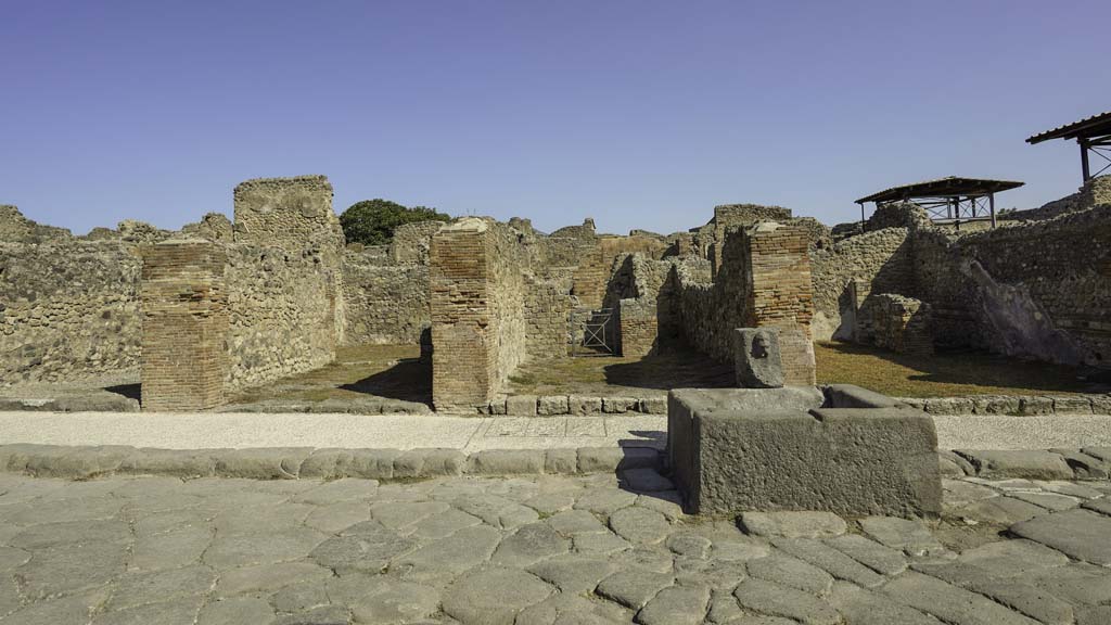 VII.14.13 Pompeii. August 2021.
Looking north on Via dell’Abbondanza towards shop at rear of fountain, on left. Photo courtesy of Robert Hanson.