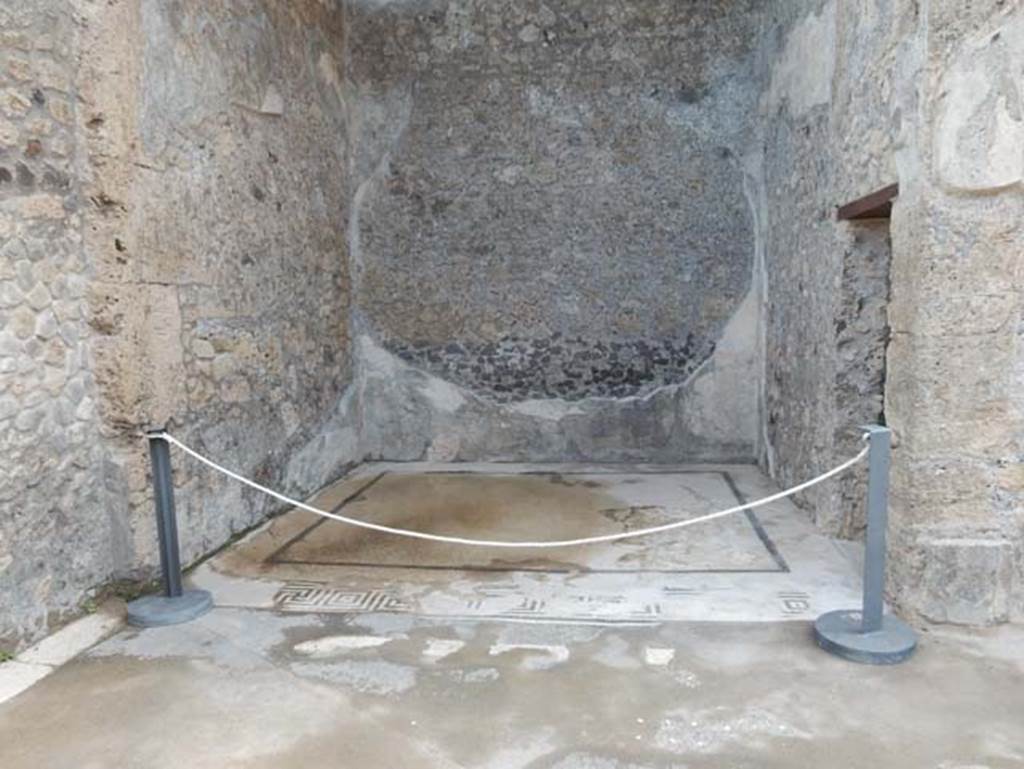 VII.15.2 Pompeii. May 2018. Looking east across ala on east side of atrium. Photo courtesy of Buzz Ferebee.
This room when discovered was described as “richly decorated with paintings and very well preserved”.
The zoccolo was painted black with architectural motifs and plants.
The middle zone was divided into panels with a yellow background, separated by white compartments in which were painted candelabra topped with eagles on globes, and at the edges were architectural decorations with shields, garlands and sphynx.
In the middle of the south wall would have been the painting with Venus fishing (pescatore).
In the middle of the east wall would have been the painting of Neptune/Poseidon with trident and dolphin.
In the middle of the north wall would have been the painting of Leda and the swan.