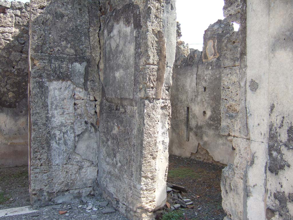 VII.15.2 Pompeii. September 2005. South-east corner of atrium.
Doorway to room to east side of entrance corridor, (on right).
This room used to have two lines of shelving along its south wall and was paved with cocciopesto.
There is a bed recess at its east end.
In this room a small square of marble was found, on which Niobe grieving for the death of her sons was depicted.