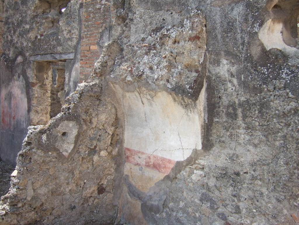 VII.15.9 Pompeii. September 2005. Looking west to south-west corner of triclinium at rear of atrium. In the recess for the bed there are remains of plaster painted with a yellow zoccolo (plinth/dado) above which was a red band, the upper wall was painted white. On the right is a circular window next to the recess.