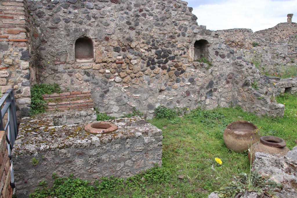 VII.16.7 Pompeii. May 2024.
Looking west towards entrance doorway, on left, counter with display shelves and inset urn/s, and west wall with two niches.
Photo courtesy of Klaus Heese.