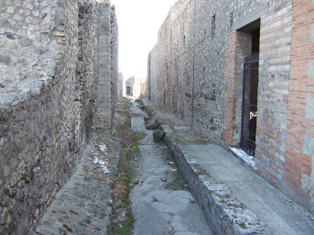 VII.6 Pompeii. September 2005. Vicolo del Farmacista, looking south. VII.16.21 on right. According to Garcia y Garcia, in 1943 the internal unexcavated area between VII.16. A and B (20 and 21) along the Vicolo del Farmacista was hit by a bomb. It fell on the soil not yet excavated and demolished the perimeter wall for a length of 4m x 3m and a part of the escarpment in two areas for 8 metres.
See Garcia y Garcia, L., 2006. Danni di guerra a Pompei. Rome: L’Erma di Bretschneider. (p.137)