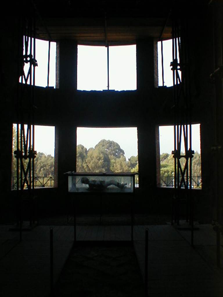 VII.16.17-22 Pompeii. September 2004. Curved apse with six windows.
A plaster cast made of a body is on display in the case.