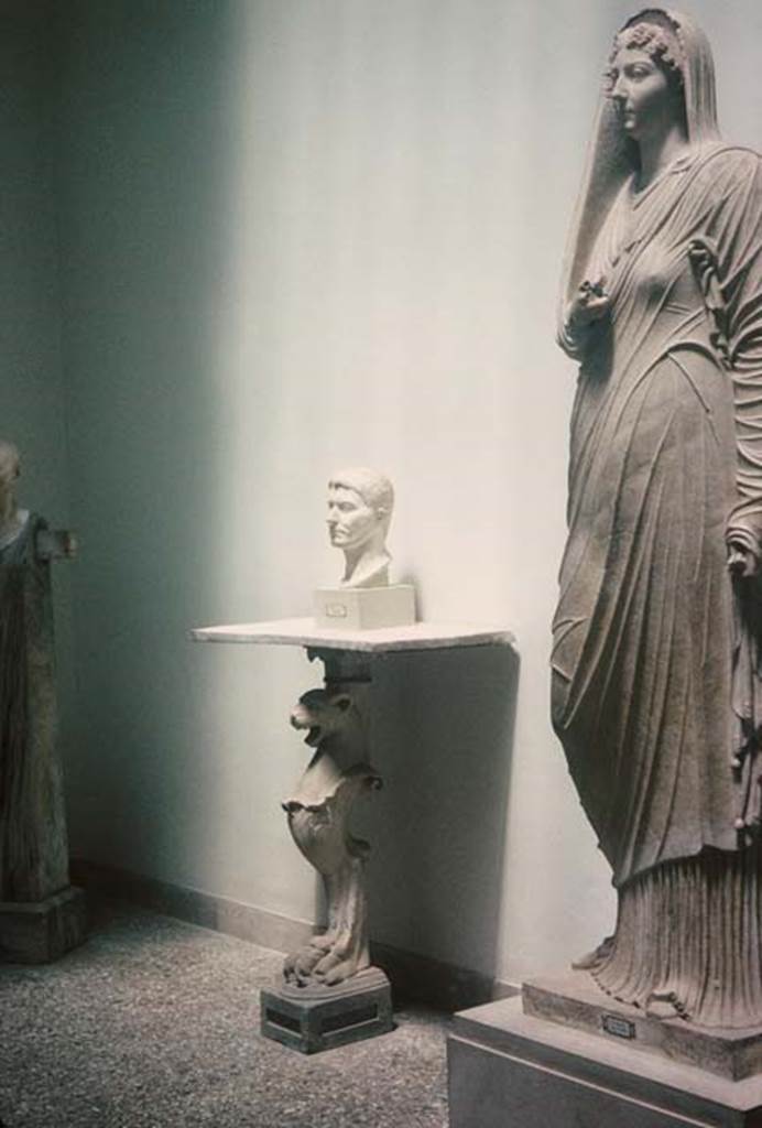 VIII.1.4, Antiquarium, Pompeii. August 1965. Sala di Livia or Room of Livia.
Marble herm of Cornelius Rufus, the bust of a Poppeo, a monopodium table and statue of Livia.
Photo courtesy of Rick Bauer.