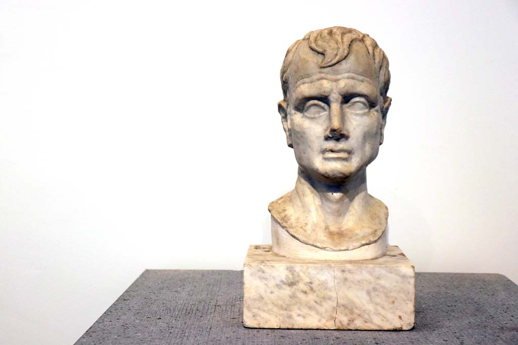 VIII.1.4 Pompeii. February 2021. Marble bust of a man, from VI.16.7. Photo courtesy of Fabien Bièvre-Perrin (CC BY-NC-SA).
According to Maiuri, (p.106 above) –
displayed in the Room of Livia and of Pompeian Portraits, were two heads found in the House of the Golden Cupids at VI.16.7.
One being a portrait which was originally supported by a wooden herm, and the other an idealized head.