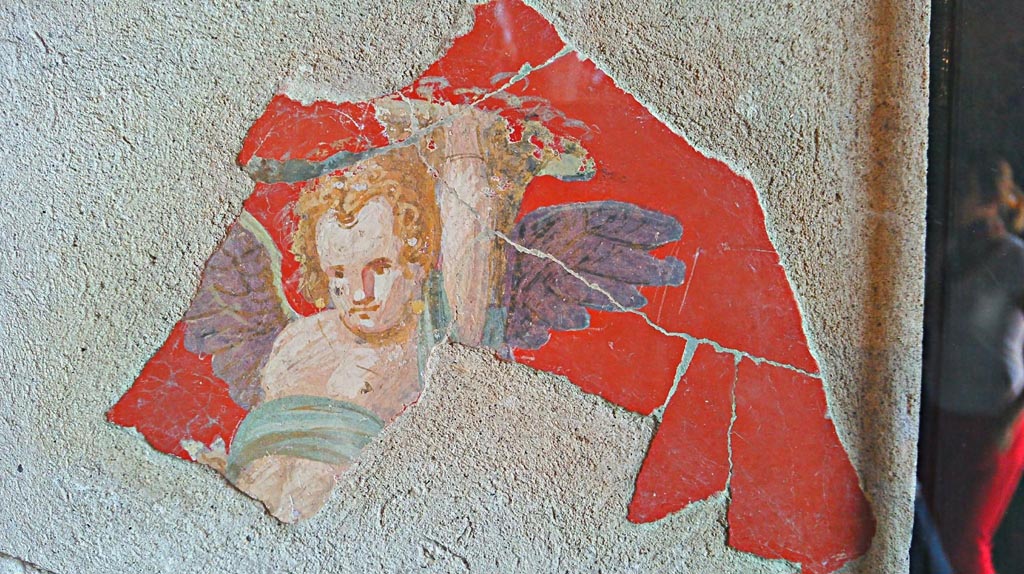VIII.2.1 Pompeii. 2018. Fragment of fresco with cupid carrying a large object on the left shoulder, perhaps a cornucopia.
Found in the lower floors of the House of Championnet. Pompeii Inventory number 14232. Photo courtesy of Giuseppe Ciaramella.