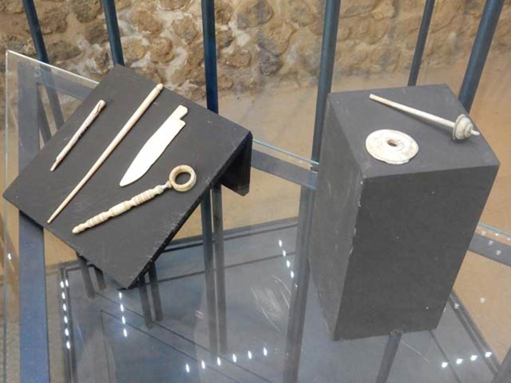 On display in Championnet complex Pompeii. May 2018. Bone items found in area to the south of the House of Championnet.
Hairpins in worked bone, used for garments or hairstyles. Pompeii inventory numbers 6313B, 6314.
Small knife. Pompeii inventory number 6329.
Spindles with small discs for weaving. Pompeii inventory numbers 6313A, 6313D.
Photo courtesy of Buzz Ferebee.