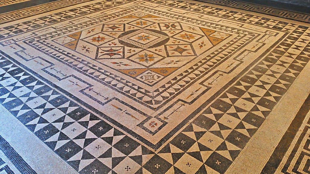 VIII.2.1 Pompeii or Villa Urbana, Varano, Stabia. July 2019.
Beautiful central emblema of coloured mosaic set into floor in Naples Archaeological Museum, “Magna Grecia” collection.
Photo courtesy of Giuseppe Ciaramella.
It is thought this central emblema may be from this house, now seen re-set into another mosaic floor.
Many artists in the 19th century have seen and drawn this mosaic in Naples Museum.
According to Abbate, this mosaic was from either Stabia or Pompeii.
According to Real Museo Borbonico, vol.15, tav 24 (XXIV), this mosaic is from the Villa of Tiberius on Capri.
According to Pisapia, this mosaic is from Stabia, Villa Urbana.
See Pisapia, M. S. 1989, in Mosaici antichi in Italia, Regione prima. Stabia, Roma, (p.67-70, no.124).
