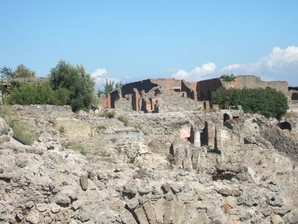 VIII.2.16 Pompeii. September 2004. Looking east towards rear of house at top of slope, and lower levels. Photo taken from exit of site. 

According to PPM � VIII.2.14-16 (p.74 and 75) � regarding rooms on lower levels -
���and those (rooms) on the west side belonged in reality to the house at nos. 3-5.�
And -
�On the lower level, and reachable by stairs towards the west, were rooms 10-13, which had mosaic flooring and remains of paintings of mediocre quality.
The rooms (14-22), about 3m higher than the rooms 10-13, were probably reachable from the house at no. 3, even if built in the same building phase�.
(For photos taken of rooms 16 and 22, see VIII.2.3, pt.2). 
See Carratelli, G. P., 1990-2003. Pompei: Pitture e Mosaici. VIII. (8). Roma: Istituto della enciclopedia italiana, (p. 74 and 75). 

According to Boyce, in a kind of cave beneath the court located behind the large atrium of number 16, on the extreme edge of the slope was a sacrarium of peculiar nature.
Against the rear wall of a narrow passage was built a masonry seat.
In the wall above it, a vaulted opening led into a small cell hewn out of the rock, with its floor 0.50m below that of the outer passage.
A second masonry seat was built within the cell, back to back with that in the outer passage.
The only means of entrance into this inner chamber appeared to have been over these two seats and through the small opening above them.
Within the cella stood a rectangular masonry altar and upon the altar lay a small terracotta altar, a marble ball, and two lamps decorated with reliefs.
One of the lamps was decorated with the relief of Jupiter, the other of a rose.
See Notizie degli Scavi di Antichit�, 1890, 290.
See Boyce G. K., 1937. Corpus of the Lararia of Pompeii. Rome: MAAR 14. (p.74, no.344) 
See Giacobello, F., 2008. Larari Pompeiani: Iconografia e culto dei Lari in ambito domestico. Milano: LED Edizioni. (p.246)


