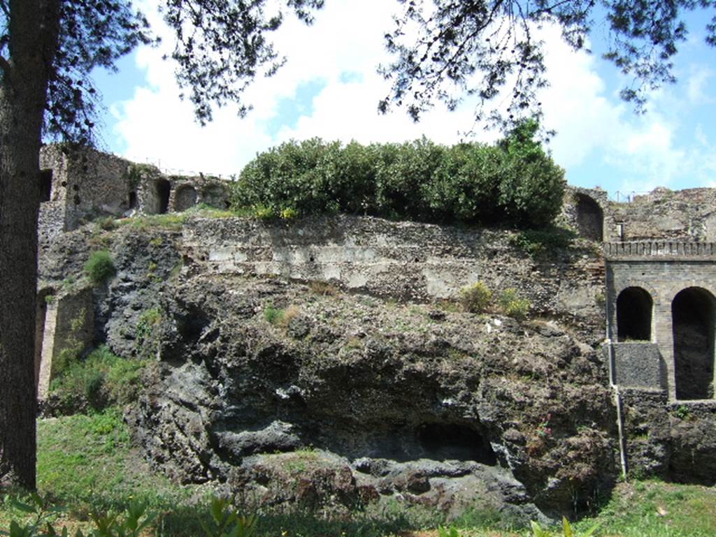 VIII.2.28, VIII.2.29, VIII.2.30 centre and VIII.2.34 from rear.
The rear garden would have been built on the volcanic ledge, behind the green bushes. According to Jashemski, in the eastern house, VIII.2.30, the rooms at the rear opened onto a narrow portico (2.20m wide) supported by columns joined by a wooden fence. A few steps led down from this portico to the small garden which had been built over and beyond the city wall by constructing a support wall on the lava ledge.
In the middle of the garden was a pool. On the street level, the rooms at the rear of this double house opened onto two wide terraces from which there would have been a magnificent view. See Jashemski, W. F., 1993. The Gardens of Pompeii, Volume II: Appendices. New York: Caratzas. (p.208)