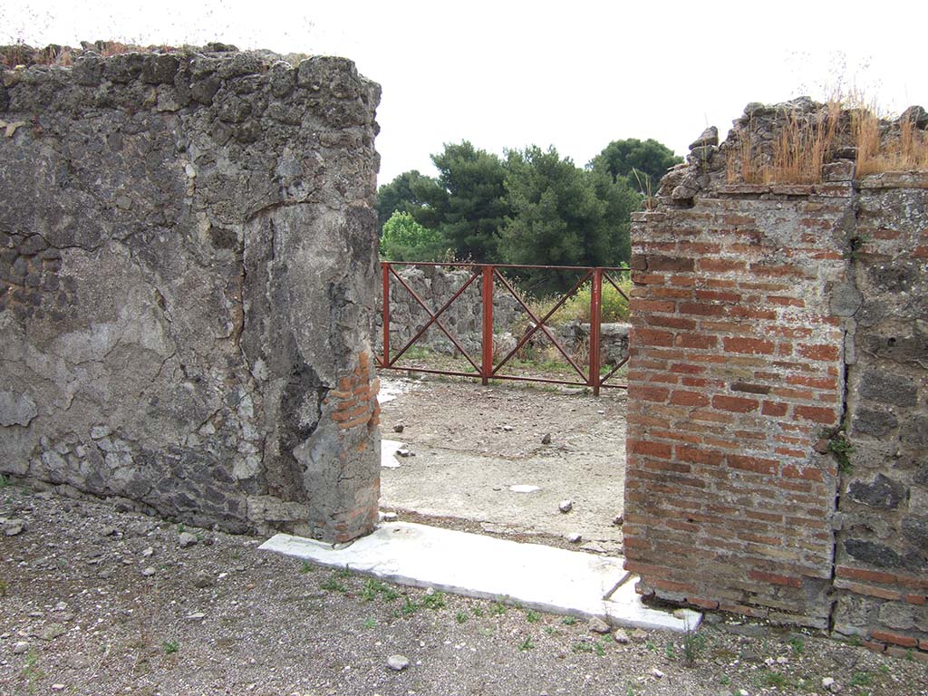 VIII.2.34 Pompeii. May 2006. Looking south. Room ‘n’, the doorway to oecus or triclinium in south wall of east ala/south-east corner of atrium.
The floor, hardly preserved today, was made of a white mosaic with small tiles (tesserae) without any border.
In the centre would have been the emblema with the doves on a basin, derived from a model by Sosos of Pergamon and admired by Pliny.
The emblema is now in the Naples Archaeological Museum, see below.