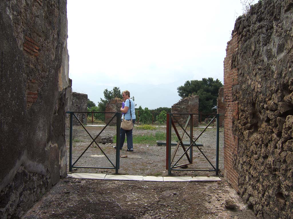 VIII.2.34 Pompeii. May 2006. Looking south from entrance fauces or corridor, towards atrium.
According to Mau, the floor of the entrance corridor was separated from the atrium flooring by a threshold of white marble with some dark veining;
at its ends you could see the holes for the door hinges.
There were no bolts; so, to fasten the door closed there were no other means than to unite the two shutters, either with a lock or some other way.
See Mau, Bullettino dell’Instituto di Corrispondenza Archeologica (DAIR), 1886, (p.149).