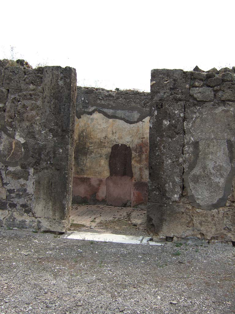 VIII.2.34 Pompeii. May 2006. Doorway to cubiculum ‘g’, on east side of atrium, next to east ala.
The threshold was of travertine with housing for the hinges of the door with two shutters opening towards the Interior of the room, like those of all the other rooms around the atrium.
The walls were decorated with a red zoccolo partitioned into simple geometric panels.
In the middle of the walls, the red central panel was separated from the yellow side panels by a narrow white panel.
The upper zones of the walls were completely faded, but conserved a trace of a stucco cornice.
On the east wall, visible through the doorway, the large hole made by previous excavators or perhaps by burrowers after the eruption, can be seen.