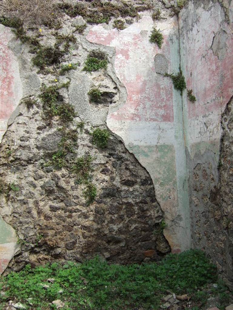 VIII.2.34 Pompeii. May 2006. Room ‘3’, north wall with remains of painted wall decoration in lower rear room. Above a high red zoccolo with a yellow cornice whose mouldings were made in light brown, the middle zone was green, topped with a white band with fake red cornice that signalled the attachment of the upper red zone. Inserted in the wall were the beam holes for the wooden floor supports of an upper floor.