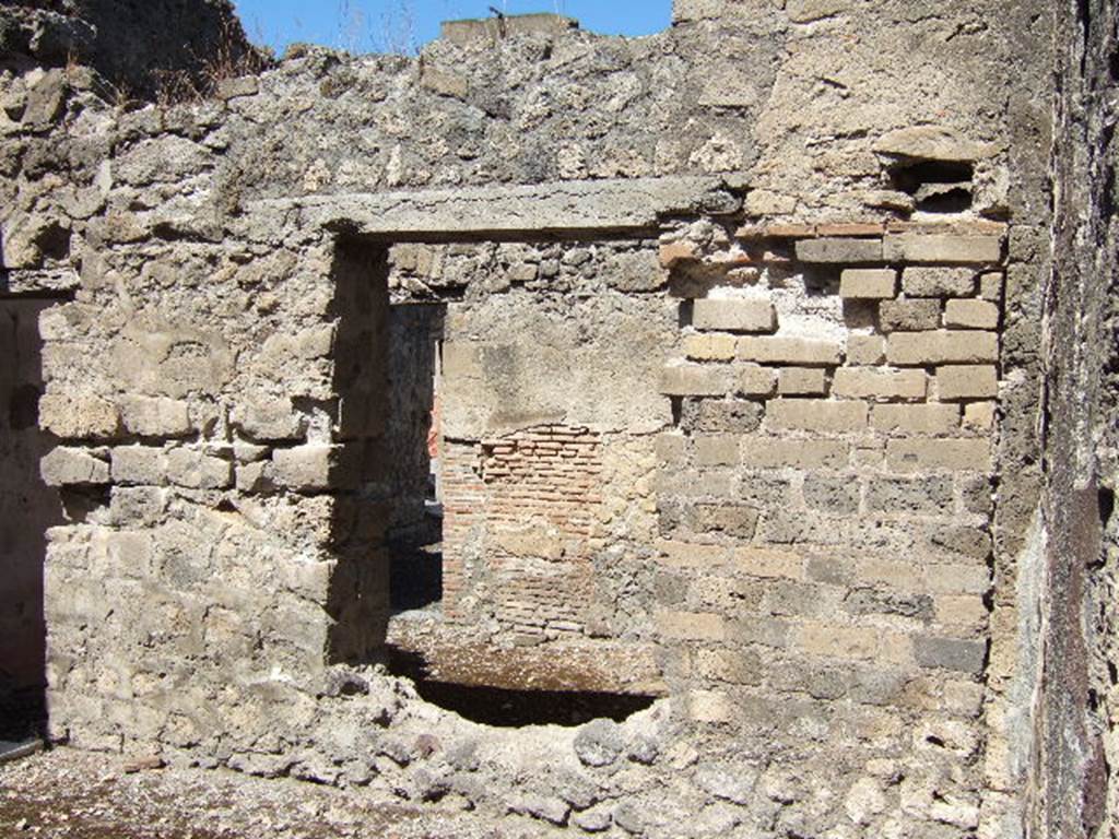 VIII.3.12 Pompeii. September 2005. Looking north from entrance across yard/courtyard, through window into triclinium.
On the north wall of the triclinium (seen through the window), in the red painted zoccolo was a panel with a painted plant. 
The middle area of the wall was painted white.
According to Breton, found in this room was a painting showing Urania pointing at the celestial globe with a baton. 
Even in 1870, Breton said it had nearly faded and disappeared.  
The other paintings in the house had entirely disappeared.
The house was named from a painting of the Three Graces, which was also lost.
See Breton, Ernest. 1870. Pompeia, Guide de visite a Pompei, 3rd ed. Paris, Guerin, (p.454). 

