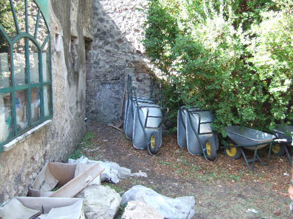 VIII.3.14 Pompeii. September 2005. West side of garden with doorway to small room or cupboard on west side of cubiculum. At the rear of the wheelbarrows are steps to an upper floor.