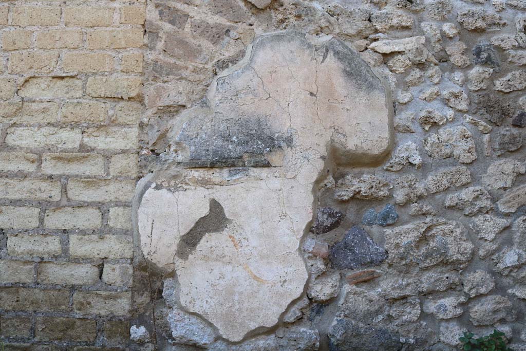 VIII.6.3 Pompeii. December 2018.
Looking towards west wall in kitchen, with remains of lararium painting. Photo courtesy of Aude Durand.
According to Boyce, on the west wall of a room which was perhaps a kitchen, was a partially preserved lararium painting.
In the upper zone, the feet of the Genius, to the right of him, a Lar in red and blue tunic, again to the right a long staff, perhaps with sausages attached to it.
Below the figure of the Genius, a tile was embedded in the wall to hold offerings.
Below this, was a serpent (black with a yellow belly, red crest and beard) advancing towards a second serpent (smaller and all black with crest).
This second serpent was coiled around a black omphalos covered with a green net and standing upon a rectangular base.
See Boyce G. K., 1937. Corpus of the Lararia of Pompeii. Rome: MAAR 14. (p.78, no.373)
According to Giacobello, the picture on the west wall of kitchen has not been conserved.
The small service area was located in the south-west corner of the house.
See Giacobello, F., 2008. Larari Pompeiani: Iconografia e culto dei Lari in ambito domestico. Milano: LED Edizioni. (p.204).