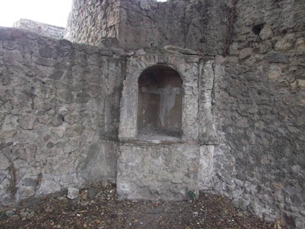 VIII.6.6 Pompeii. December 2007. Niche in south-west corner.
According to Boyce, this simple aedicula consisted on a podium and a niche with an arched opening. The interior of the niche is an unusual pentagonal shape, the floor is paved with red stucco ornamented with little white stones. The rest of the structure was uniform white, except for the tympanum, which was yellow with a star in white relief in the middle. Before the shrine and close to the south wall, stood a small masonry altar, originally coated with white stucco. See Boyce G. K., 1937. Corpus of the Lararia of Pompeii. Rome: MAAR 14. (p.78, No.374, Pl.33,1)