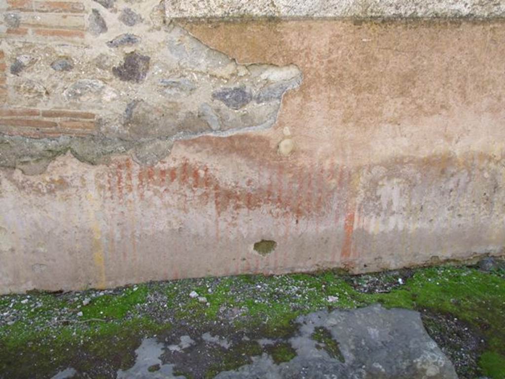 VIII.6.7 Pompeii. March 2009. Vicolo della Parete Rossa. Remains of painted decoration on outside wall on east side of entrance.
According to PPM,
The plaster that covered the zoccolo was painted in a false marble with red veins in the central panel and yellow veins in the side ones.
The red vertical veins, painted on the protruding plinth of cocciopesto, are more intense than the yellow ones placed on the sides
(Le venature verticali rosse, dipinte sullo zoccolo sporgente di cocciopesto, sono piu intense di quelle gialle poste ai lati
L’intonaco che copre la parete in opera incerta con cantonale in laterizi, era nello zoccolo a falsi marmi con venature rosse nel pannello centrale e venature gialle in quelli laterali.)
See Carratelli, G. P., 1990-2003. Pompei: Pitture e Mosaici, VIII. Roma: Istituto della enciclopedia italiana, (p.684, and figs. 47 and 48, on p.686).