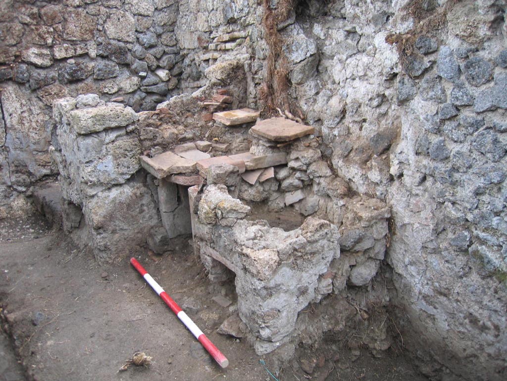 VIII.7.10 Pompeii. August 2005. Looking south-east in kitchen area towards hearth at east end of south wall.
The remains of the lararium niche may be partly visible on the upper right of centre of the photo.
Photo courtesy of Pompeii Archaeological Research Project: Porta Stabia.
According to Mau -
“Next to the hearth there was the usual painting of the Lares, and a niche.”
See Mau in BdI, 1875, (p.167) (p.166-169 below_- La quarta casa).