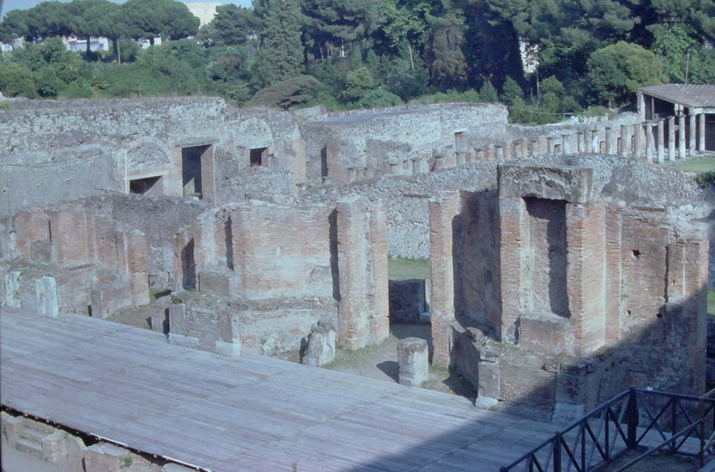 VIII.7.21, Pompeii. 7th August 1976. Looking south-east towards stage, from top of theatre.
In the background, top right, are the columns in the Gladiator’s Barracks.
Photo courtesy of Rick Bauer, from Dr George Fay’s slides collection.