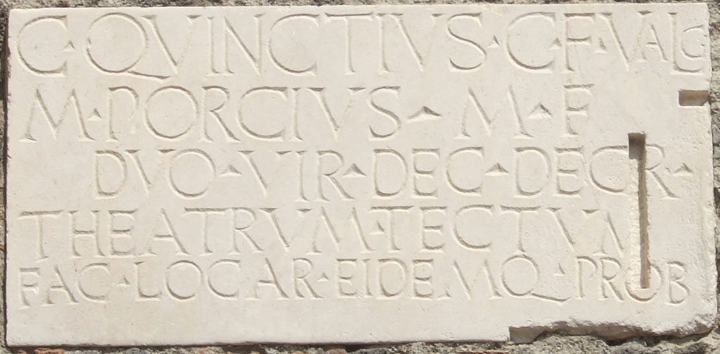 VIII.7.21 Pompeii. September 2005. Dedication plaque on wall by the entrance from the large theatre to the small theatre.
C QVINCTIVS C F VALG
M PORCIVS M F
DVO VIR DEC DECR
THEATRVM TECTVM
FAC LOC AR EIDEMQ PROB
 
C(aius) Quinctius C(ai) f(ilius) Valg(us) 
M(arcus) Porcius M(arci) f(ilius)
duovir(i) dec(urionum) decr(eto)
theatrum tectum 
fac(iundum) locar(unt) eidemq(ue) prob(arunt)    [CIL X 844b]
 
Gaius Quinctius Valgus, son of Gaius, and Marcus Porcius, son of Marcus, duumvirs, by decree of the town councillors awarded the contract for the construction of the covered theatre and also approved it.
See Cooley, A. and M.G.L., 2004. Pompeii: A Sourcebook. London: Routledge. (p.20, B9). CIL X 844=ILS 5636.
 
A Theatrum Tectum was a covered theatre; in this case it refers to the Small Theatre or Odeon in Pompeii.

According to Cooley, two copies of this inscription were set up near the main entrances to the Covered Theatre.
See Cooley, A. and M.G.L., 2014. Pompeii and Herculaneum: A Sourcebook. London: Routledge, B11, p. 29-30.
This one is from the entrance from the Large Theatre to the small theatre and a second was from the entrance on Via Stabiana.
