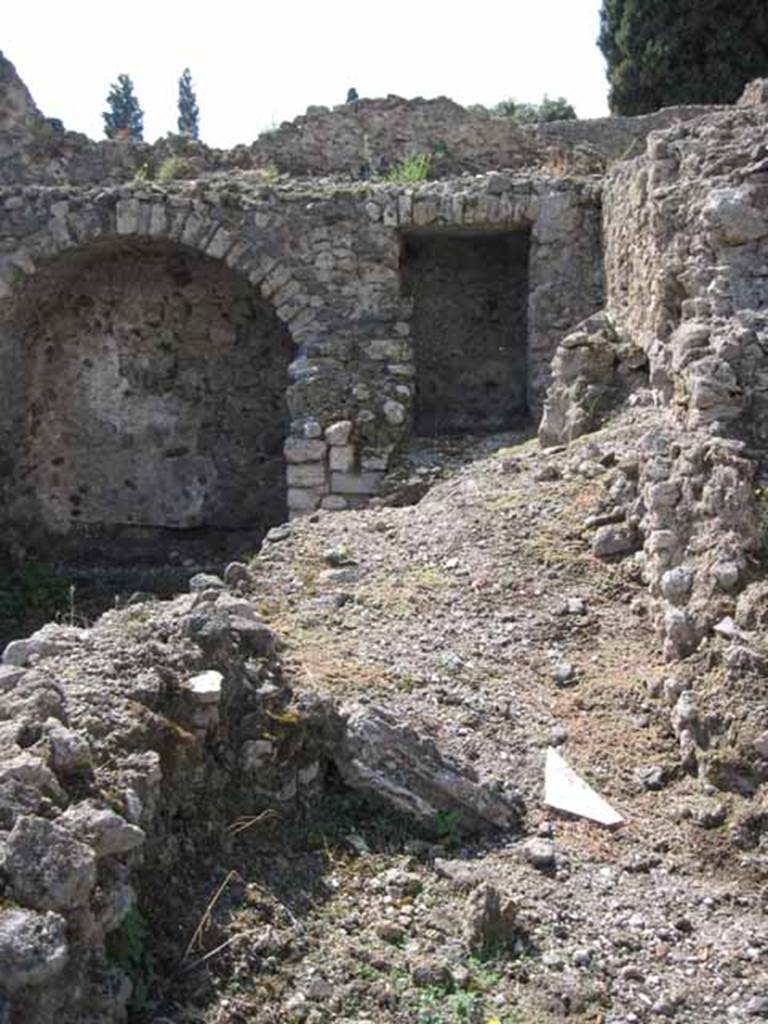 VIII.7.22 Pompeii. September 2010. Looking west from kitchen area of VIII.7.23, into corridor area of VIII.7.22. Photo courtesy of Drew Baker.
The area on the right side of the picture would seem to be the area of the lararium which would have been on the north wall of the corridor, see below. Although Boyce described the lararium as being in an arched niche, his measurements would make the one in the picture above, on the west wall and too big. According to Boyce, in the north wall of a corridor leading from the underground kitchen to the posticum of VIII.7.22, was a large arched niche. This was I.0 metre high, 0.85 wide, 0.50 deep and 0.70 above the floor. The back wall of the niche was painted red, and on it was the figure of Fortuna, clad in a green tunic and yellow mantle. In her left hand she held a cornucopia, and in her right, a rudder. To the left of her feet was a large globe.
The side walls of the niche and the area under the feet of the goddess were decorated with green plants.
See Boyce G. K., 1937. Corpus of the Lararia of Pompeii. Rome: MAAR 14. (p.78, no:378)
Fiorelli describes, VIII.7.22 as a corridor belonging to VIII.7.24, with stairs to upper floor. Nearby is the kitchen, in which remains the niche of the Penates, with the image of Fortuna with cornucopia and rudder.
See Pappalardo, U., 2001. La Descrizione di Pompei per Giuseppe Fiorelli (1875). Napoli: Massa Editore. (p.134)