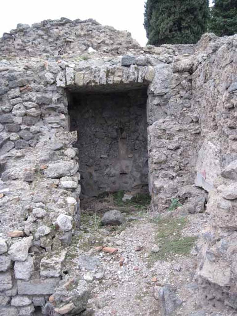 VIII.7.22/23/24 Pompeii. October 2010. Looking west to doorway to corridor to lower rooms from VIII.7.22/23, access is to the right through the doorway. Photo and information courtesy of Drew Baker/Gareth Beale/Hembo Pagi.
Somewhere in this corridor area, Boyce described a lararium.
According to Boyce, in the north wall of a corridor leading from the underground kitchen to the posticum at VIII.7.22, was a large arched niche.
This was I.0 metre high, 0.85 wide, 0.50 deep and 0.70 above the floor.
The back wall of the niche was painted red, and on it was the figure of Fortuna, clad in a green tunic and yellow mantle.
In her left hand she held a cornucopia, and in her right, a rudder.
To the left of her feet was a large globe.
The side walls of the niche and the area under the feet of the goddess were decorated with green plants.
See Boyce G. K., 1937. Corpus of the Lararia of Pompeii. Rome: MAAR 14. (p.78, no:378)
Fiorelli describes, VIII.7.22 as a corridor belonging to VIII.7.24, with stairs to upper floor.
Nearby is the kitchen, in which remains the niche of the Penates, with the image of Fortuna with cornucopia and rudder.
See Pappalardo, U., 2001. La Descrizione di Pompei per Giuseppe Fiorelli (1875). Napoli: Massa Editore. (p.134)
