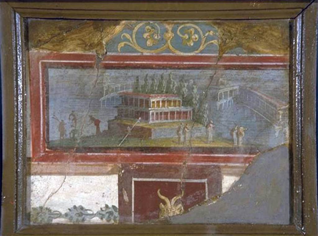 VIII.7.28 Pompeii. On 1st March 1766, three fragments were found on the ground at the west end of the north portico.
According to P.P.M., these were reassembled to form a square on the upper part of the western section of the north wall.
In addition to the picture with landscape also preserved is part of the decorative context in which it was inserted.
The picture shows in the foreground a small island on which there is a building with two storeys of porticoes erected on a high podium and closed at the back by a row of cypress trees.
On the right, toward the shore, there are five cloaked figures and two other on the left, next to an ithyphallic statue. In the background are some arcaded buildings on stilts.
At the top of the fresco, resting on the picture frame, is a pediment with scrolls.
Below the picture frame is a dark red panel with the head of a goat.
To the side of the red panel is a tight garland on a white background.
The remarkable freshness of the colours and the legibility of the picture were probably the reasons that led the excavators to recover the three fragments.
Now in Naples Archaeological Museum. Inventory number 9490.
See Carratelli, G. P., 1990-2003. Pompei: Pitture e Mosaici: Vol. VIII. Roma: Istituto della enciclopedia italiana, p. 742.