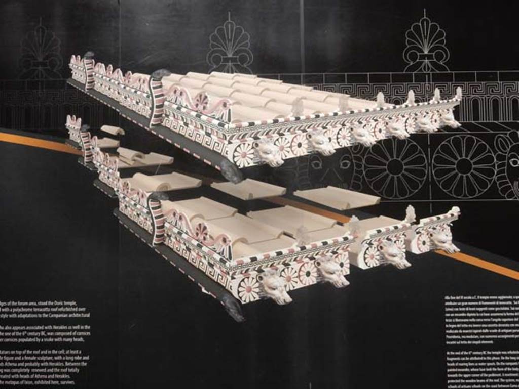 VIII.7.31 Pompeii, May 2018. Roof reconstruction drawing from information notice-board.
On the long side ran a cornice (sima) with the heads of roaring lions as waterspouts.
On the ramparts was a flat band with a painted meander whose base took the form of the body of a snake with heads facing towards the upper corner of the pediment.
A revetment plaque with guilloche (an engraved pattern of spirals, intertwining bands etc.) in relief protected the wooden beams of the roof.
Photo courtesy of Buzz Ferebee.