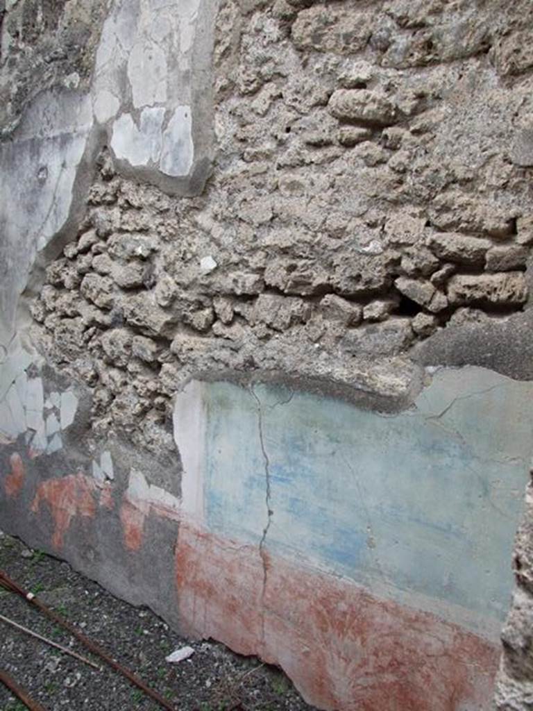 IX.1.22 Pompeii. December 2007. Room 9, remains of painted plaster. According to Bragantini, the dado in this room was red and painted with plants separated by narrow divisions. The middle zone was painted with blue panels edged with borders with triangles, separated by narrow divisions. Some fragments were put back in situ, after the 1943 bombing.
See Bragantini, de Vos, Badoni, 1986. Pitture e Pavimenti di Pompei, Parte 3. Rome: ICCD. (p.400, cubicolo ‘c’)