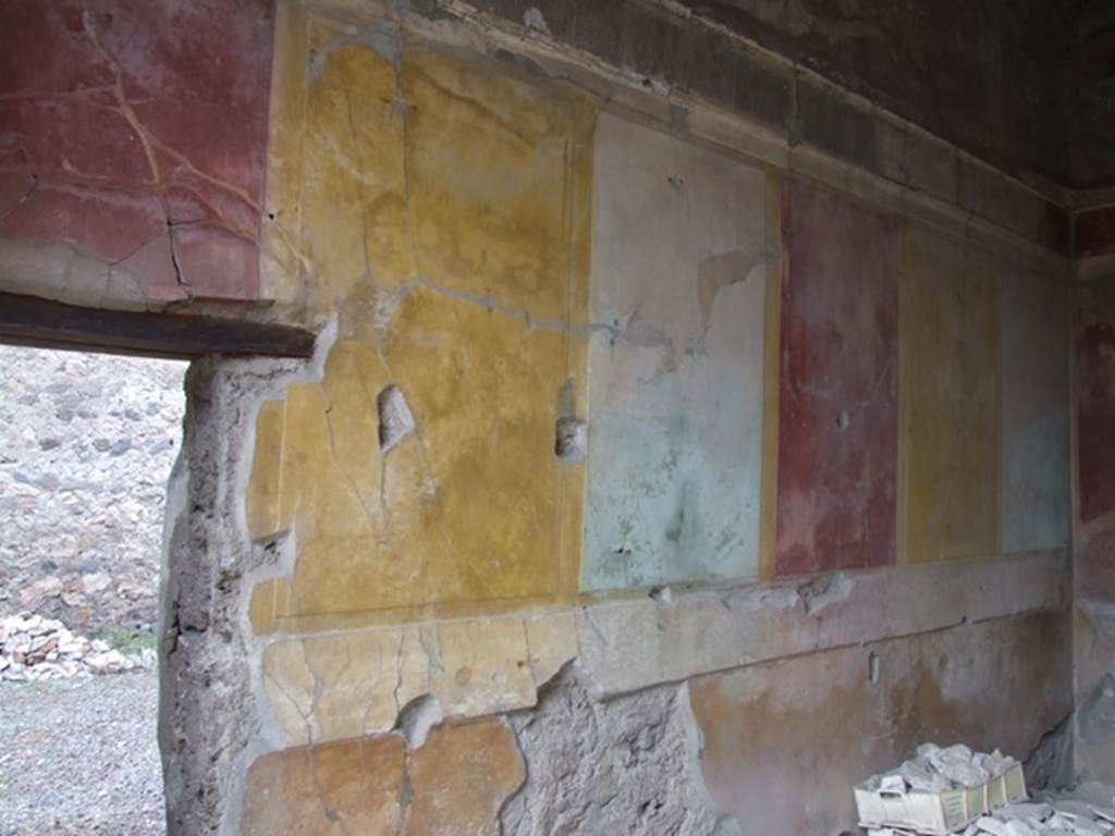 IX.1.22 Pompeii. December 2007. Room 25, west wall of room in north-east corner of peristyle. Starting from the left the figures seen in the small rectangular panels would have been –
a) A man, walking half to the left and half towards the viewer. He was naked, but held a robe with both hands which fell from behind the lower part of his body, and was visible between his legs. Each of his hands held a border.
b) Two wrestlers who could be named Hercules and Antaeus. The one on the right had embraced the opponent from behind and held him up high resting him on the thigh – but it was not possible to distinguish whether it was on the right or left. This one painfully took with the left hand the left arm of his conqueror.
c) A naked man, who put the stretched left leg towards the right, whilst the right leg was curved behind. The right arm was stretched from the shoulder towards the right, and it seemed as if his hand was disproportionately large, as if armed with a boxing-glove. Probably here one recognised a boxer.
d) Very faded. I seem to recognise a standing figure turned to the left, which could have been a boxer, corresponding to figure c).
e) A female figures in long robe. It seemed that the head was seen faced forward but that the rest of her moved towards the right; with her right hand extended from which hung an object, not recognisable. The left hand held a long stick, either a spear or a sceptre, from the top of which, a line nearly horizontal stretched above her head.
f) A man, walking quickly half to the right, half towards the viewer, with the curved right leg put forward. Holding a shepherd’s crook in his right hand, with the curved part up, whilst near to the right shoulder as if leaning on it, was a high and narrow object, but not definable.
See Mau in BdI, 1876, (p.101-2)